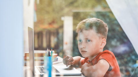 Criança distraída com janela em vez de assistir aula online